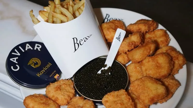 PLUS LE PRODUIT EST POPULAIRE À L’ORIGINE, PLUS SA RÉINTERPRÉTATION LUXE CARTONNE: AVEC SES NUGGETS AU CAVIAR À 75 EUROS ET SES BURGERS À LA TRUFFE, C’EST QUOI CE FAST-FOOD BEAU QUI ARRIVE EN FRANCE?